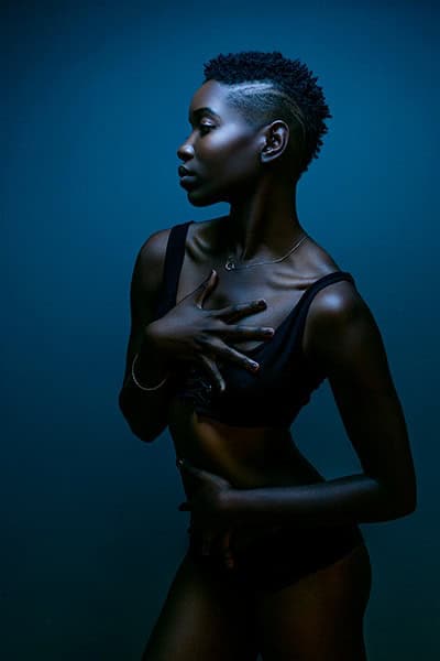 Moody boudoir image of young black girl in blue hue