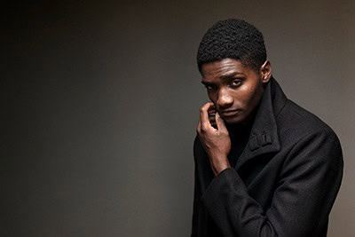 Moody portrait of young black man in dark peacoat