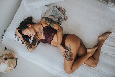 Boudoir image of tattooed girl on bed.