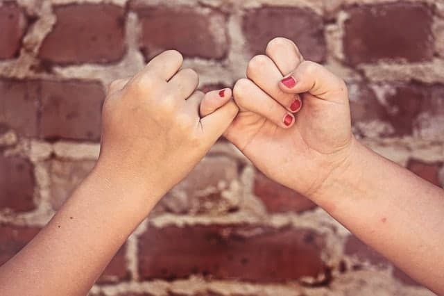 Pinky promise against brick wall