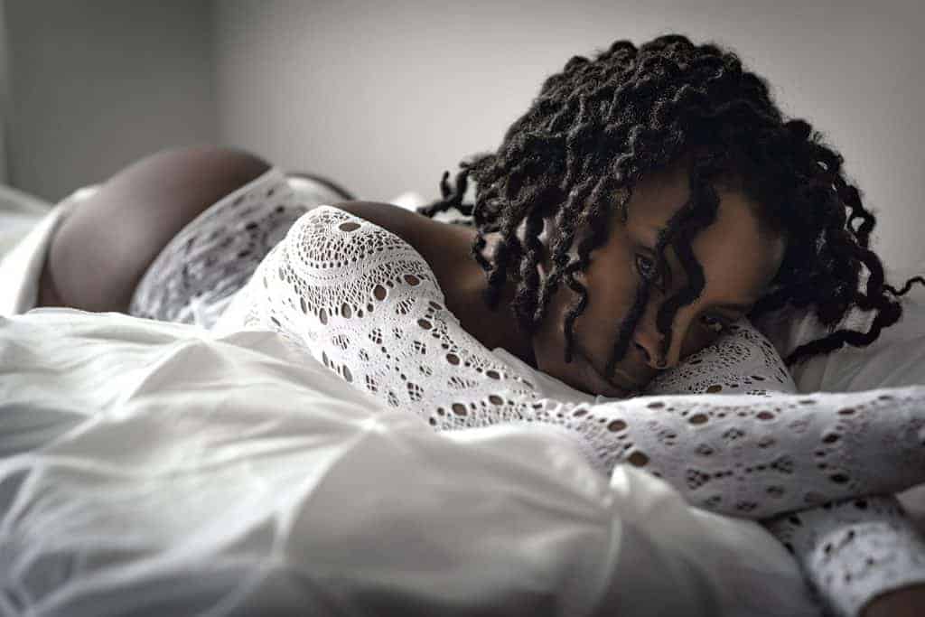 Boudoir bed pose with young black girl on stomach