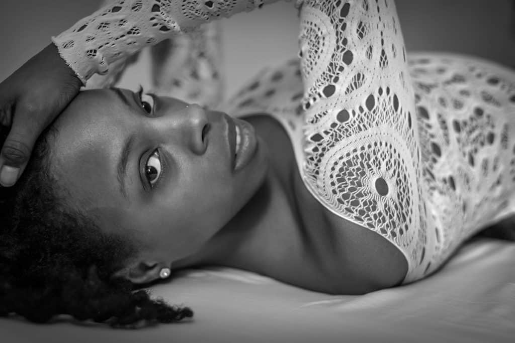 Black and white boudoir close-up of young black girl's face lying on back