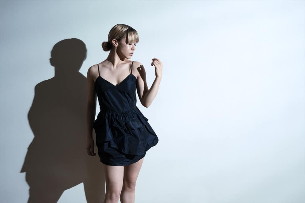 Woman and shadow against white wall