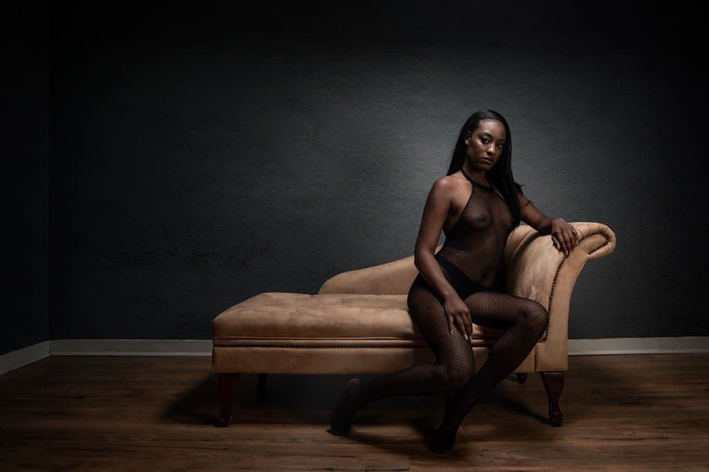 Seated boudoir pose on chaise lounge.